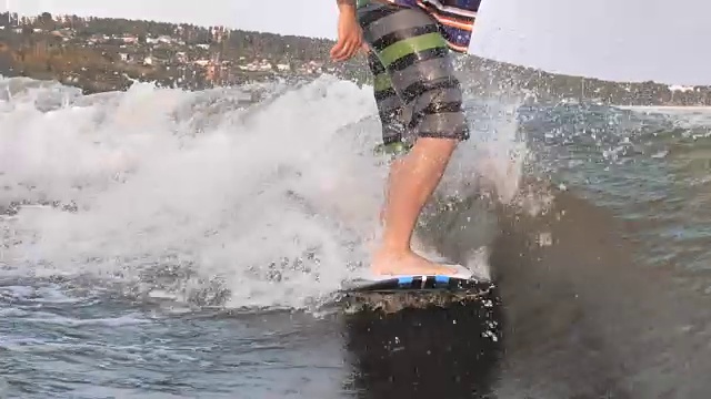 低角度的不明男子尾流冲浪。花式滑水板做的技巧视频素材