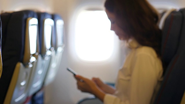 商务女性在飞机上用智能手机聊天的肖像，模糊不清视频下载