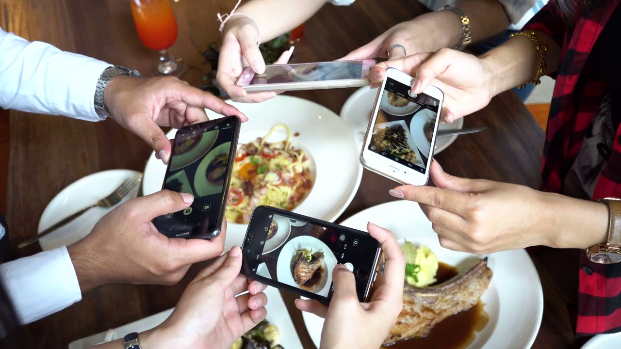 4名年轻人在餐厅用手机拍摄意大利面和食物视频下载