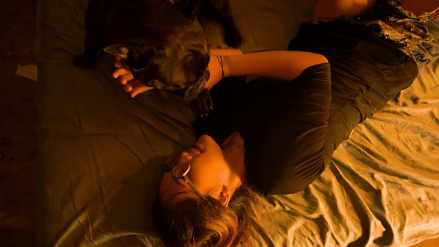 可爱的黑色法国斗牛犬喜欢与年轻快乐的亚洲女人在床上玩。视频素材