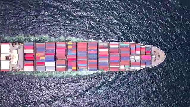 货船载着集装箱驶向港口，港口边缘有许多起重机。它是进出口经济的重要组成部分。视频素材