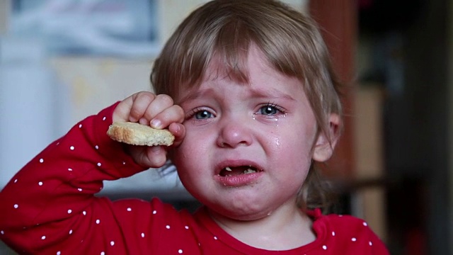 一个哭着的小女孩抱着一块干面包的肖像视频下载