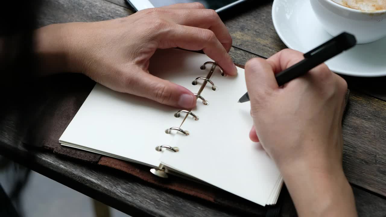 特写女人在笔记本上写下2019年的目标，新年计划，在木桌上喝咖啡视频素材