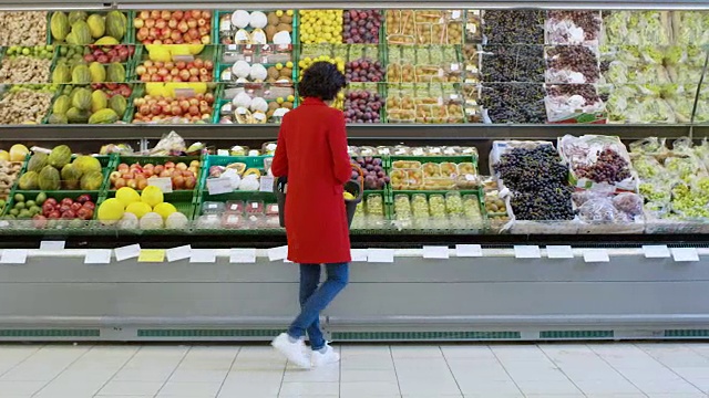 在超市:女士在商店的新鲜农产品区选择有机水果。她拿起哈密瓜，把它们放进购物篮里。后视图。视频素材