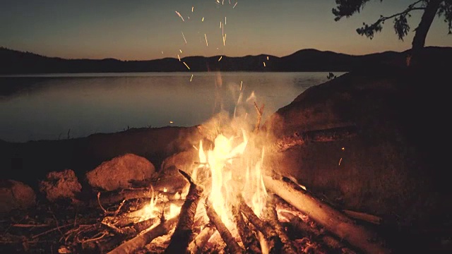 湖边的壁炉里燃起了篝火，在夜里。视频下载