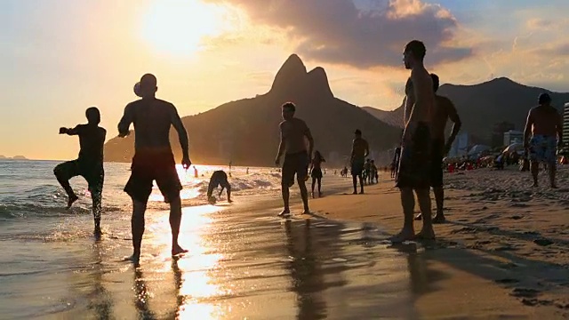 日落时分，年轻人在海滩上踢足球视频下载