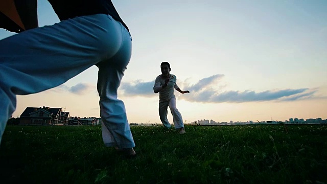 日落时分，两个运动员在草地上互相打斗视频素材