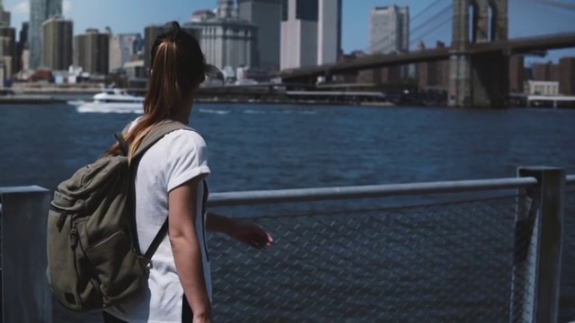 美丽的年轻女游客背包走在纽约金融中心天际线全景在一个阳光明媚的日子视频素材