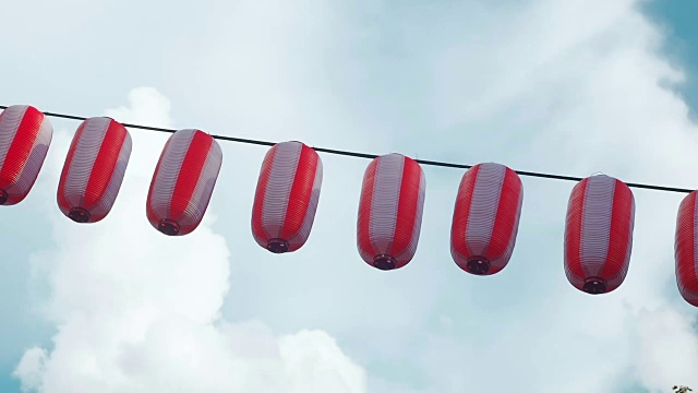 纸上红白相间的日式灯笼挂在蓝天阴云的背景上视频素材