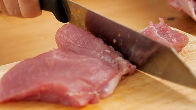 厨师的手在木板上切猪肉。视频素材