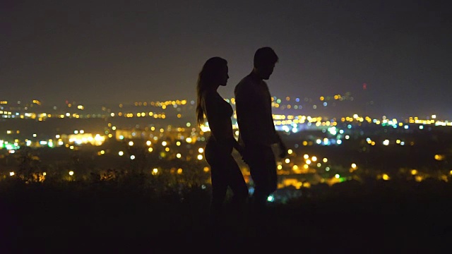 这对情侣以城市的灯光为背景接吻。晚上的时间视频素材
