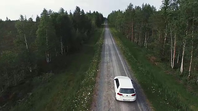 鸟瞰图，后面的汽车行驶在乡村道路上的森林。飞过笔直的砾石路视频素材