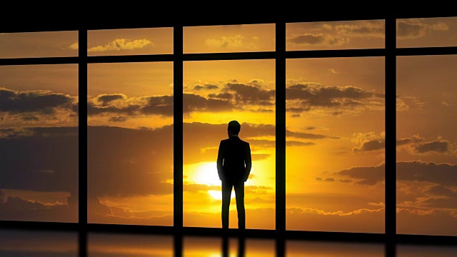 这个男人站在日落背景的全景窗户旁。时间流逝视频素材