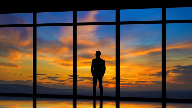 在日出的背景下，站在窗边的男人。时间流逝视频素材