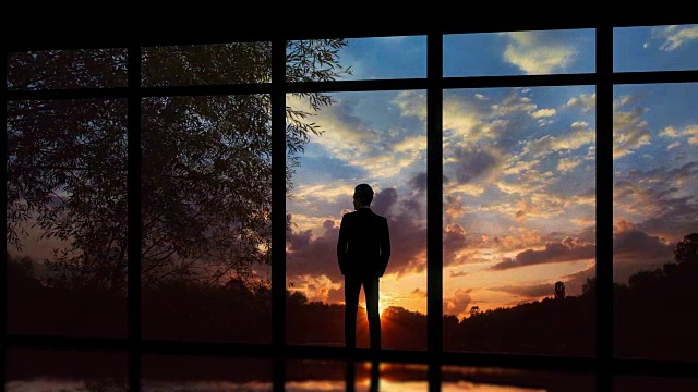 在夕阳的背景下，站在窗边的男性。时间流逝视频素材