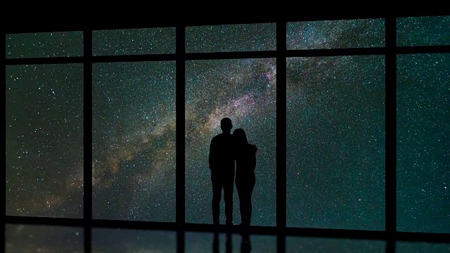 这对情侣站在流星雨背景的窗户附近。时间流逝视频素材