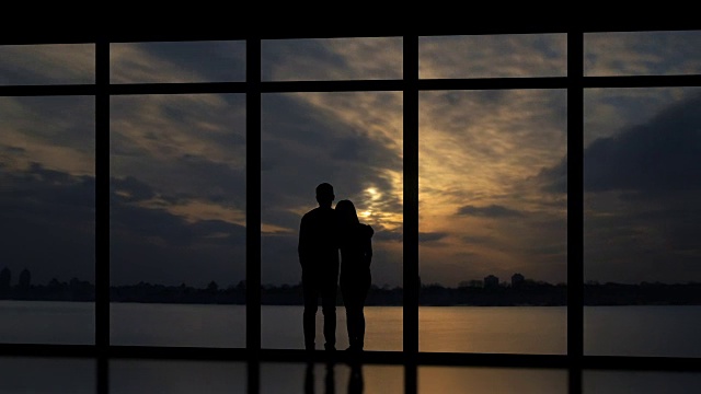 在日落的背景下，一男一女站在窗边。时间流逝视频素材