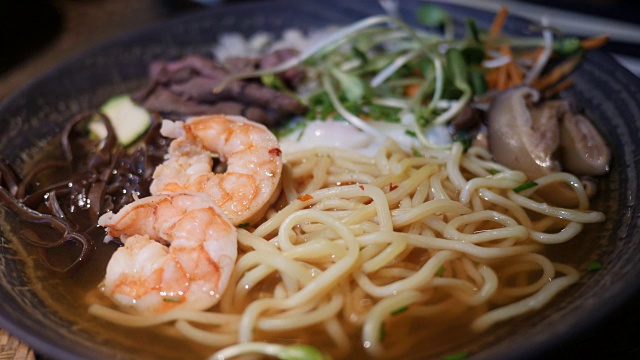 拉面是一种传统的日本汤，里面有虾、肉、蔬菜和面条。4 k视频素材