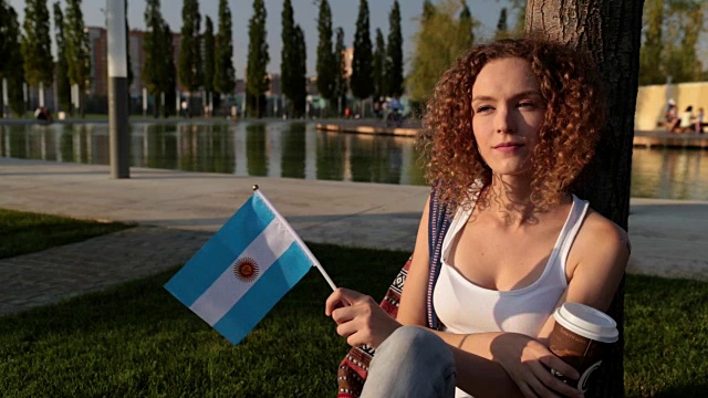 公园里美丽的女游客举着阿根廷国旗。视频下载