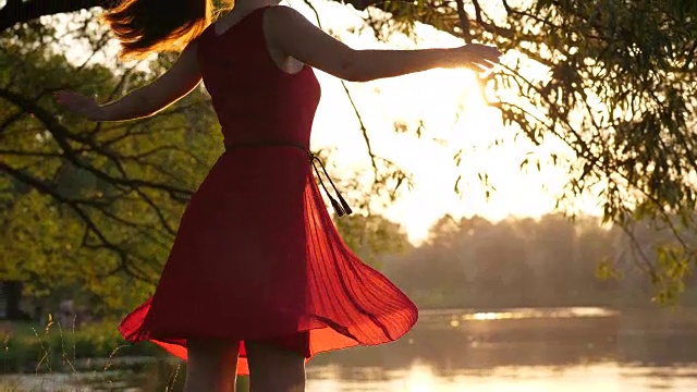 身着红色透明连衣裙的女子在日落时分的湖面上翩翩起舞视频下载