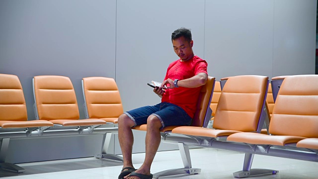 亚洲旅行者在等待飞机航班时使用手机视频下载