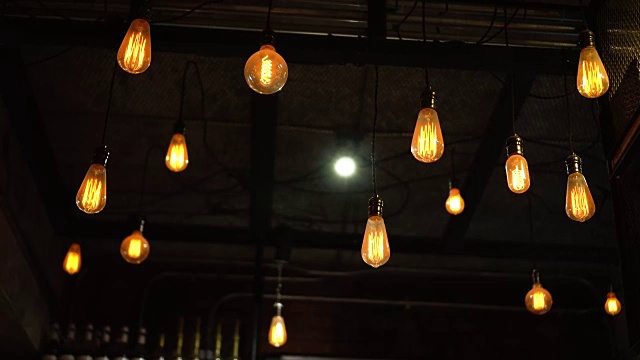 复古复古的黄色灯泡悬挂在咖啡馆晚上的黑暗背景。视频素材