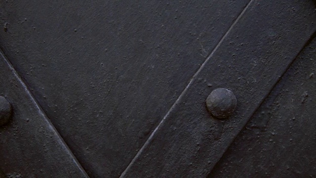 一扇老式的黑色金属门，用镶板加固。视频素材
