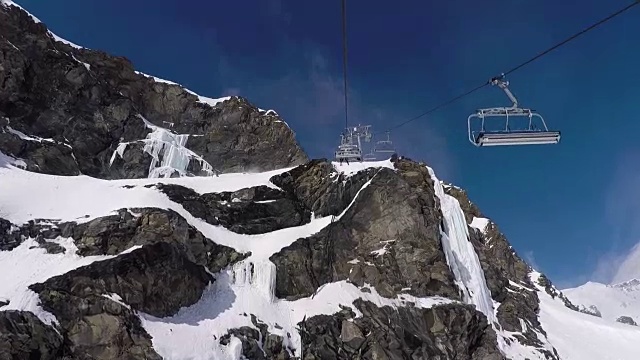 在冬季滑雪胜地，座椅升降机上升到山顶的岩石视频素材
