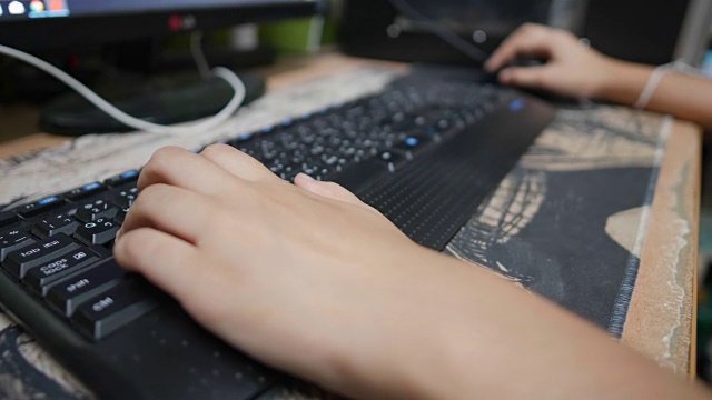 近距离亚洲妇女的手工作和玩游戏的桌子上的一个电脑键盘在家里。视频素材