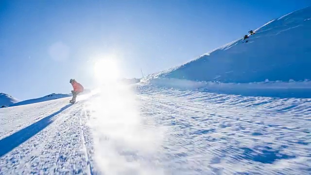 在一个阳光明媚的日子里，滑雪者从滑雪坡上滑下来，雪花向他喷来视频素材