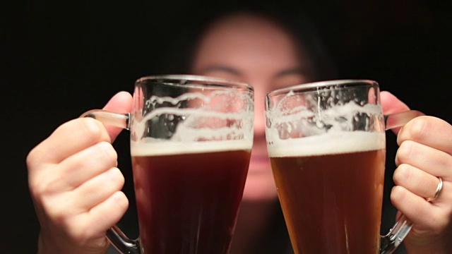 一个愚蠢的女人拿着生啤酒庆祝，拿着两个大杯子为自己祝酒。女孩喝啤酒时表现得很傻视频素材