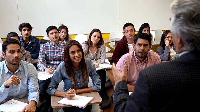 一群拉丁美洲的学生看起来很投入，注意听老师笑，并举手视频下载