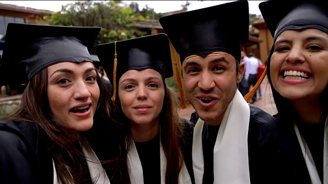 一群年轻的朋友在自拍做鬼脸庆祝他们的毕业视频素材
