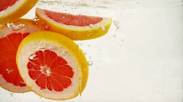 柚子橙子片落入水中，溅起水花和气泡，慢镜头特写视频素材