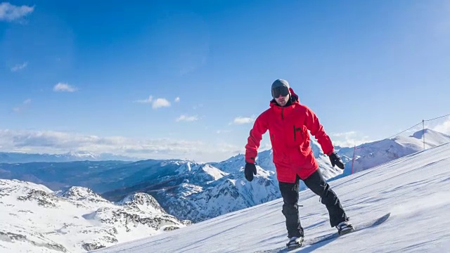 滑雪者沿着滑雪坡滑行，将雪喷洒到以山为背景的摄像机中视频素材