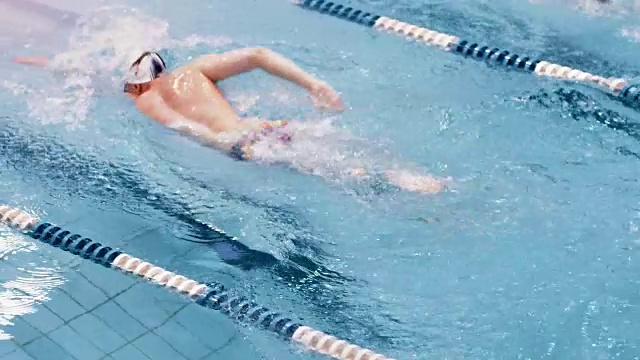 高角度欧洲游泳运动员戴着护目镜和帽子漂浮在游泳池的轨道上视频下载