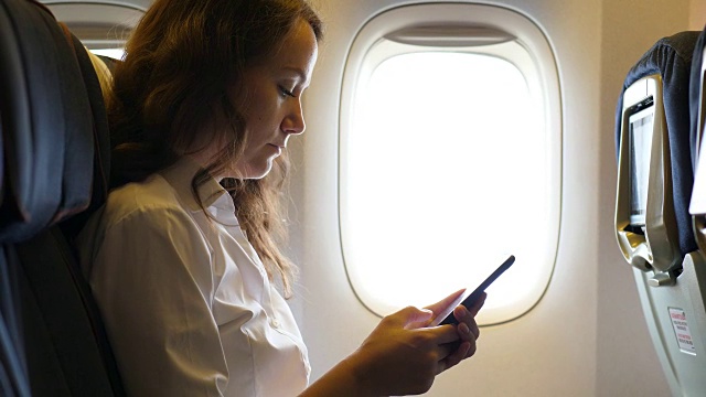 有智能手机的女人坐在飞机靠窗的地方视频下载
