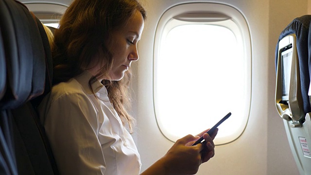在飞机上玩智能手机的忙碌女人视频下载