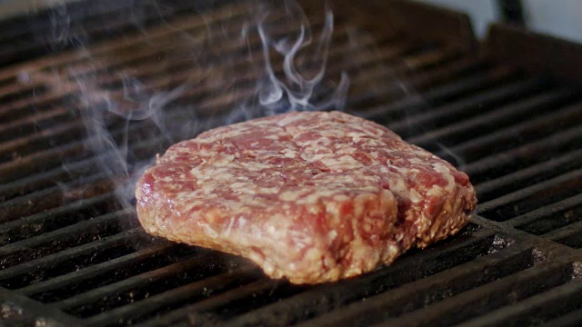 慢动作的牛肉汉堡在烧烤在近距离与火焰和烟雾视频素材