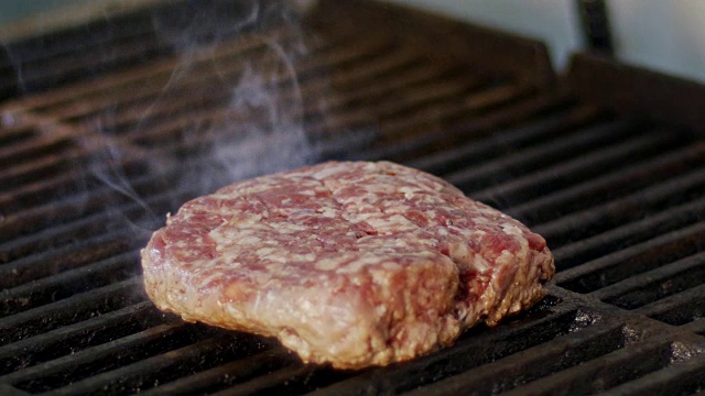 慢动作的牛肉汉堡在烧烤在近距离与火焰和烟雾视频下载