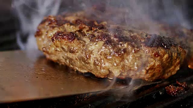 慢动作的牛肉汉堡在烧烤在近距离与火焰和烟雾视频下载