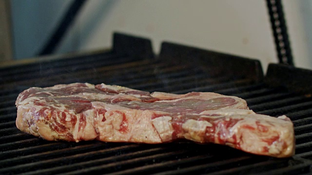 一大块牛腰牛排在木炭烤架上烤的慢动作视频素材