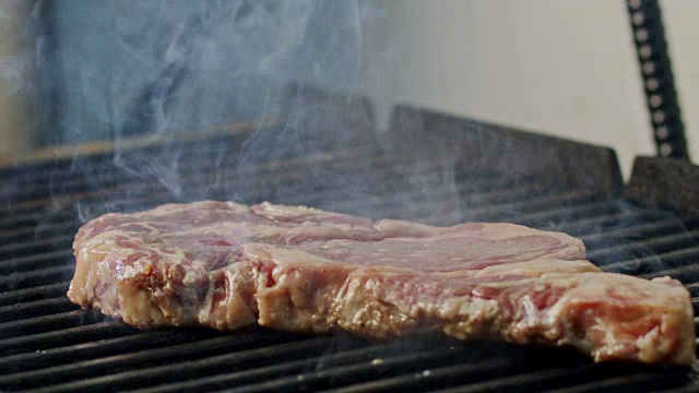 一大块牛腰牛排在木炭烤架上烤的慢动作视频素材
