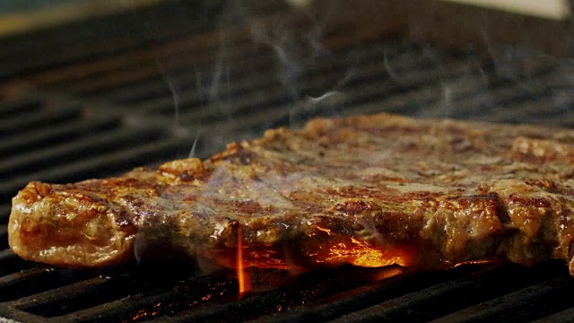 一大块牛腰牛排在木炭烤架上烤的慢动作视频下载