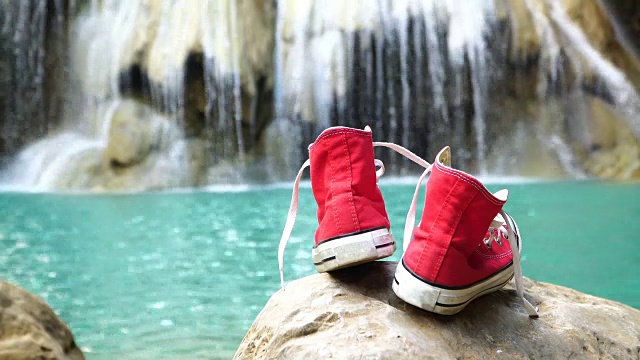 瀑布背景上的红鞋。视频下载