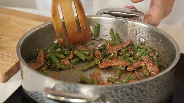 用钢锅将碎牛肉、青豆、大蒜和香草一起煎视频素材