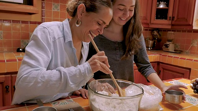 快乐微笑的墨西哥母亲和十几岁的女儿一起烘烤的慢动作视频素材