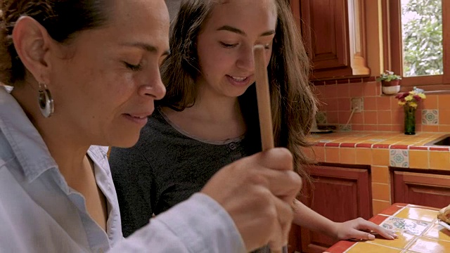 墨西哥母亲和十几岁的女儿一起烘焙的慢镜头视频素材