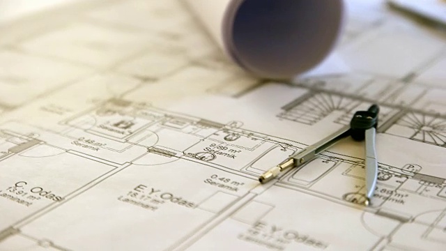 建筑师拿着铅笔工作与笔记本电脑和蓝图的建筑计划，工程师素描一个建设项目的概念。视频素材