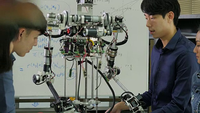 年轻的电子工程师团队在车间协作建造机器人。团队工程师一起启动机器人项目。有技术或创新观念的人。视频素材